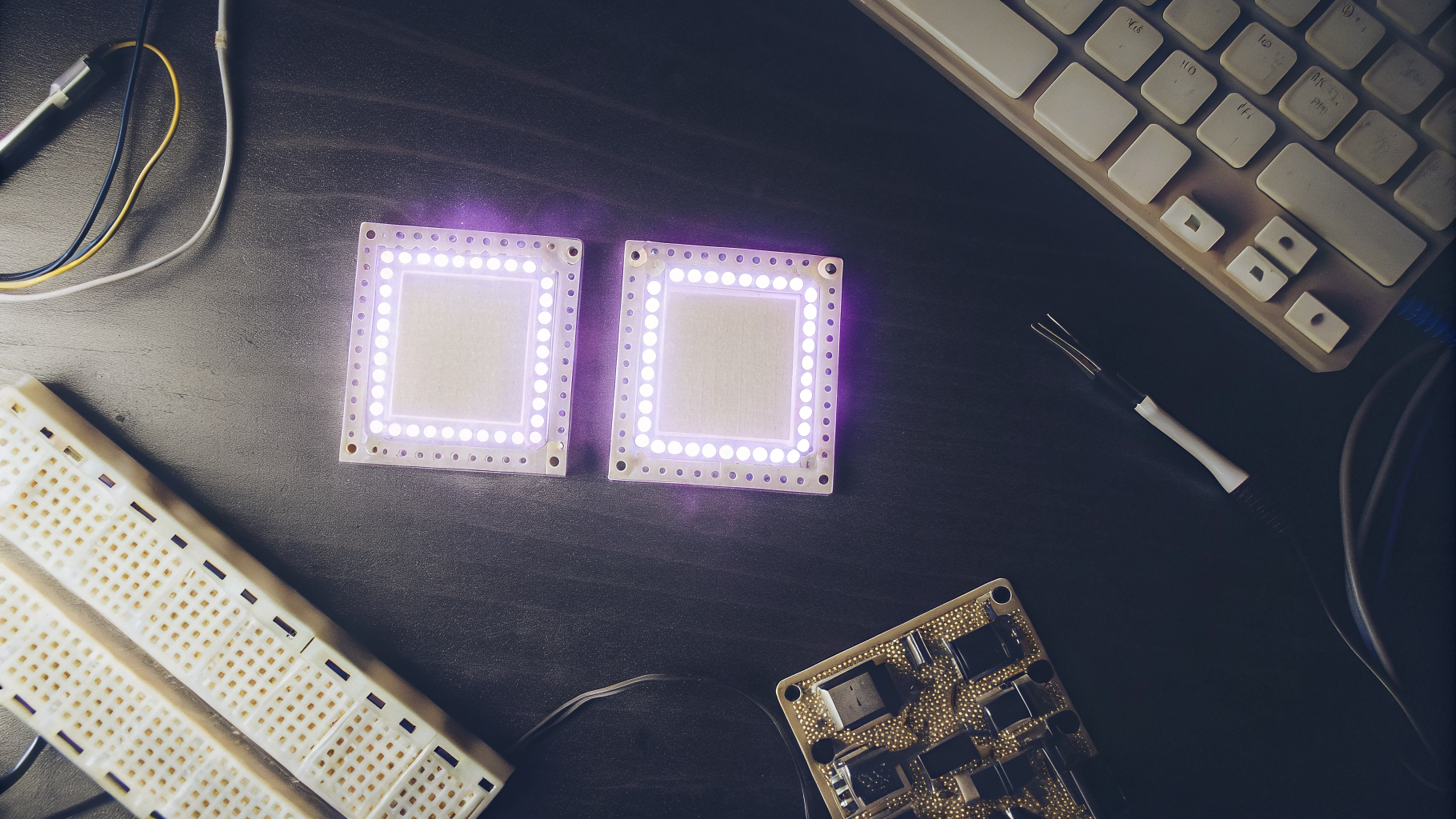 Maker workspace with development boards, breadboard, and purple LED lighting